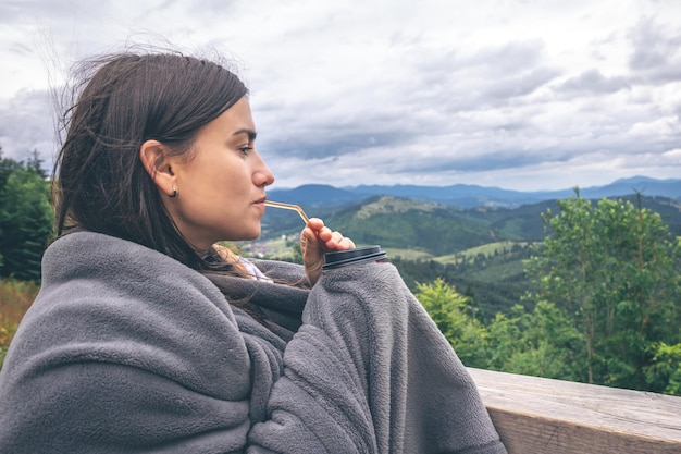 Una giovane donna che beve caffè con vista sulle montagne