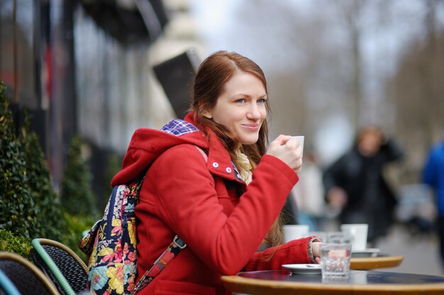 Giovane donna che beve caffè in un caffè di strada parigina