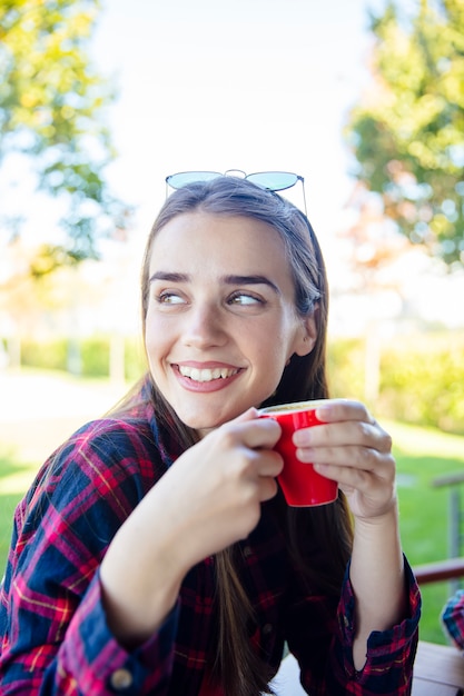 公園でコーヒーを飲む若い女性