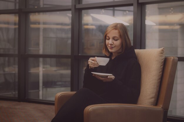 椅子に座ってコーヒーを飲む若い女性