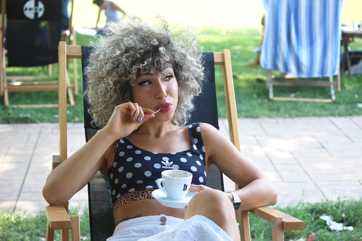 Photo young woman drinking glass while sitting on chair