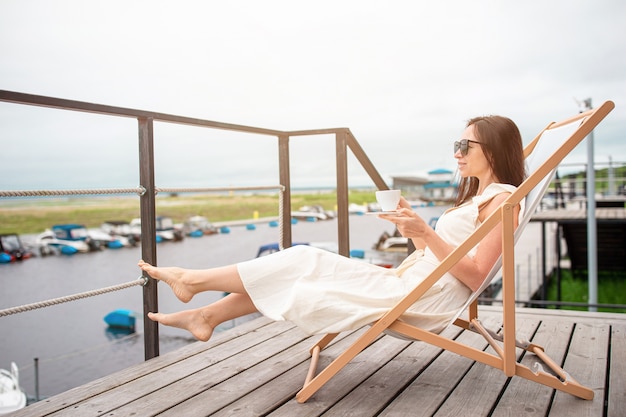 Young woman drinking hot coffee enjoying beach view.