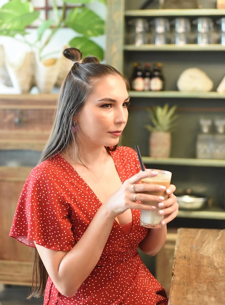 Молодая женщина пьет кофе со льдом в кафе