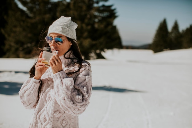 山のスキー場でレモネードを飲む若い女性