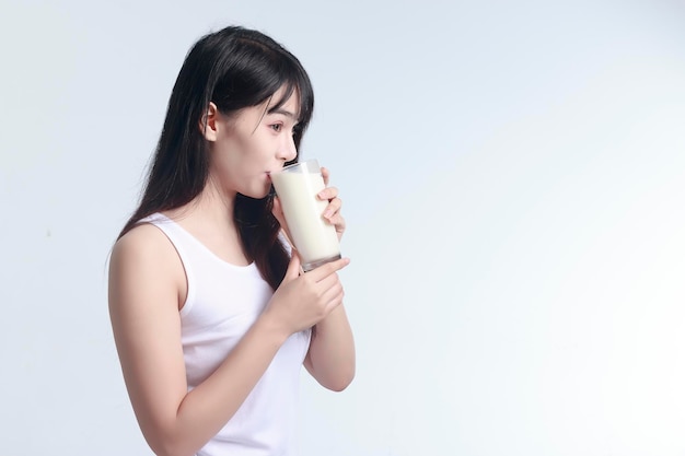 young woman drinking milk against white background