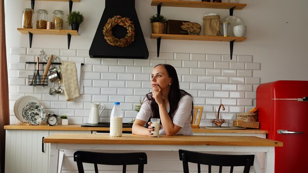 Young woman drinking milk in kitchen Adult female enjoying useful drink for breakfast