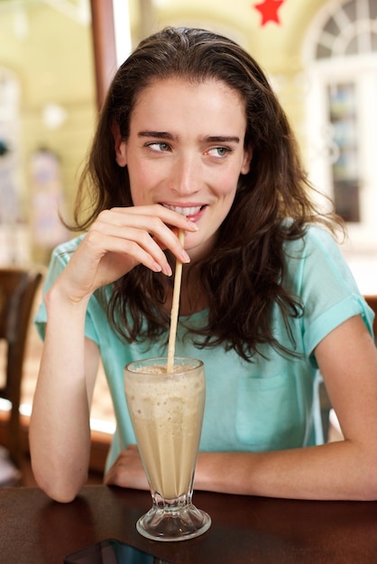 カフェでミルクセーキを飲む若い女性