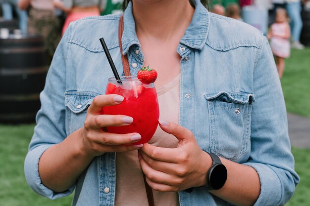 Giovane donna che beve cocktail daiquiri alla fragola o mocktail in vetro con cannuccia in estate festosa bevanda estiva rinfrescante per feste o feste