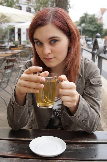 young woman drinking tea in a street cafe