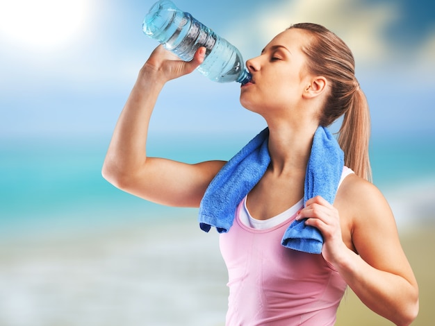 Young woman drinking water after work out