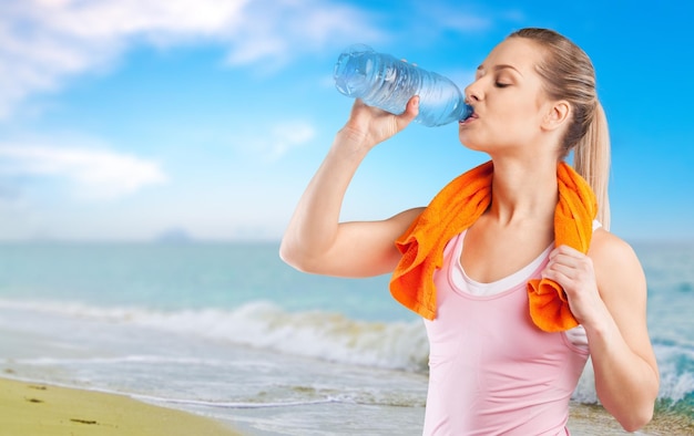 Молодая женщина пьет воду после тренировки