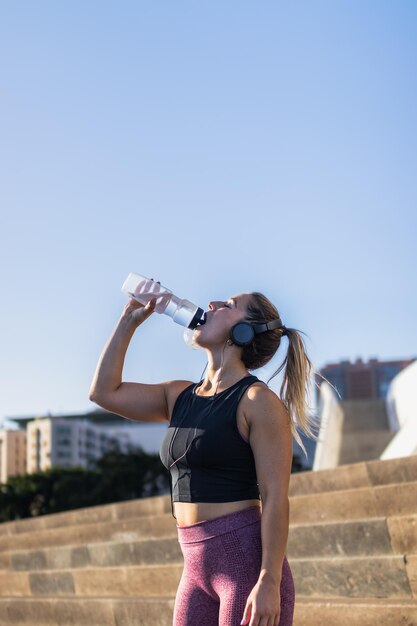 市内で運動しながら水を飲む若い女性