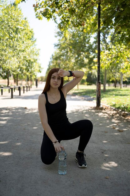 Young woman drinking water while standing on road