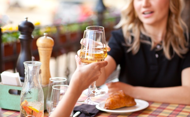 Giovane donna che beve un vino bianco in una terrazza di un caffè con gli amici