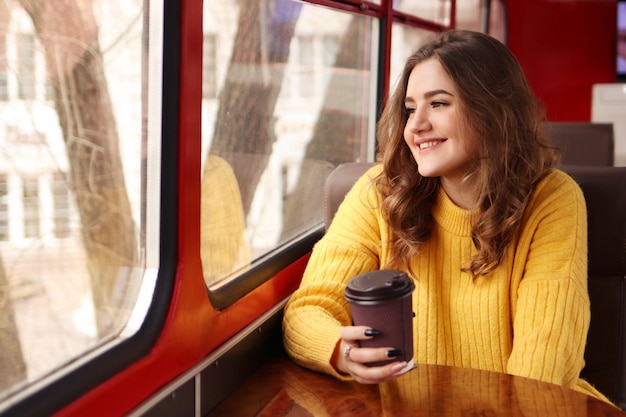 Young woman drinks coffee from paper glass