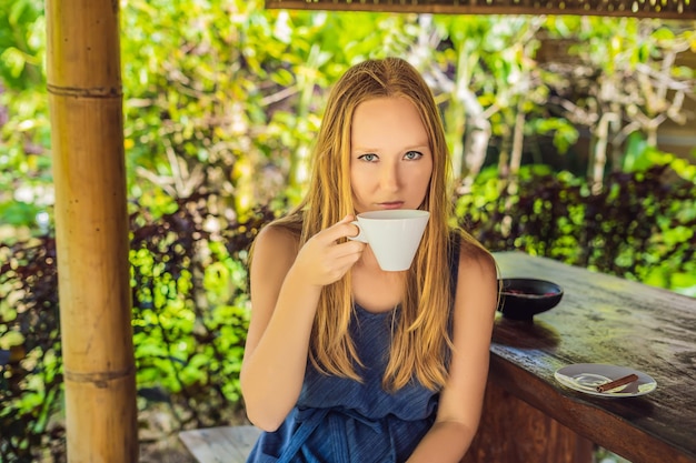 若い女性は望楼でコーヒールアクを飲みます。