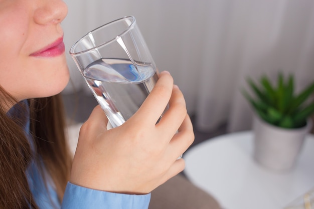 young woman drinks water from a glass