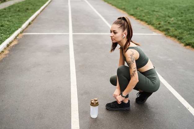 Foto la giovane donna beve acqua allo stadio al mattino