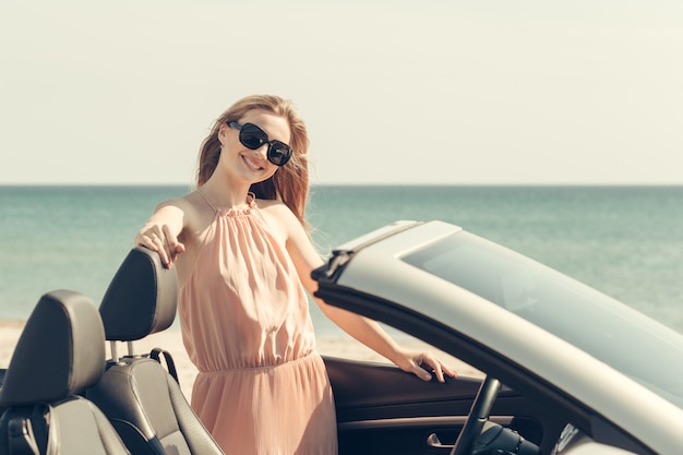 La giovane donna guida un'automobile sulla spiaggia