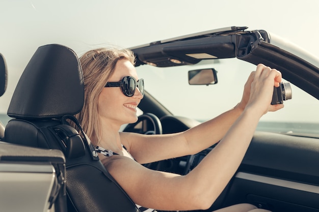 若い女性はビーチで車を運転します