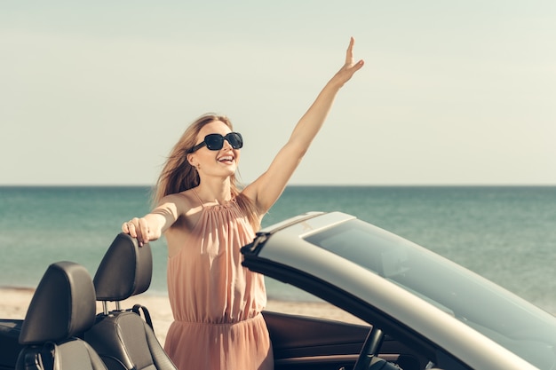 La giovane donna guida un'auto sulla spiaggia