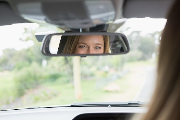 Молодая женщина в сиденье водителя, глядя в зеркало