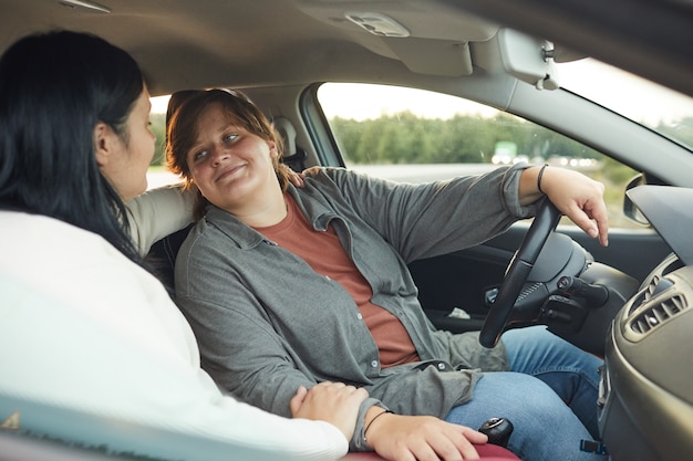 Young woman driving car talking to her girlfriend during their trip