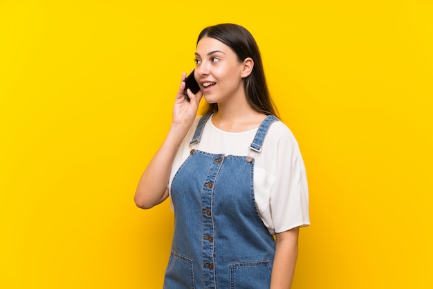 Young woman in dungarees keeping a conversation with the mobile phone