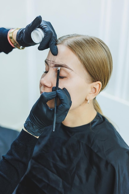 Young woman during professional eyebrow mapping procedure before permanent makeup