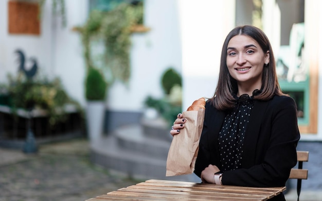 Giovane donna mangiare colazione e sorridente mangiare croissant colazione la ragazza mangia un croissant giovane donna mangiare croissant in un bar