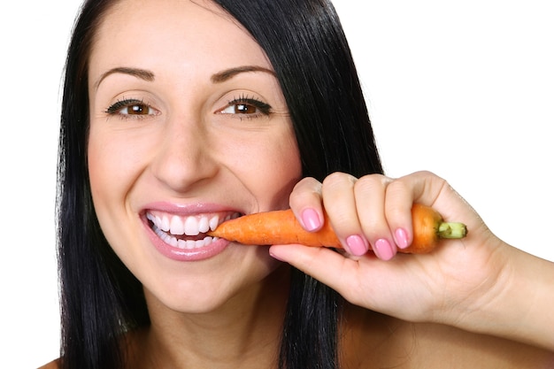 Young woman eating the carrot, over white