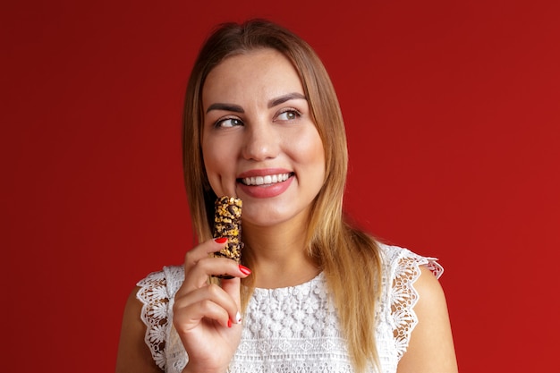 Giovane donna che mangia la barra di caramella del cereale