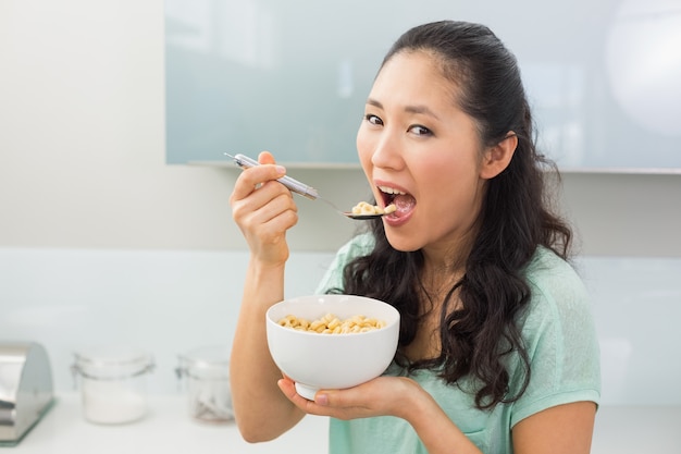 Giovane donna che mangia i cereali in cucina