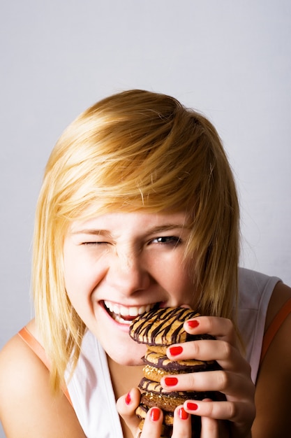 Giovane donna che mangia i biscotti di pepita di cioccolato