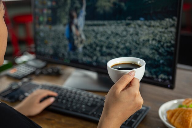 Giovane donna che mangia panini croissant nella stanza dell'ufficio