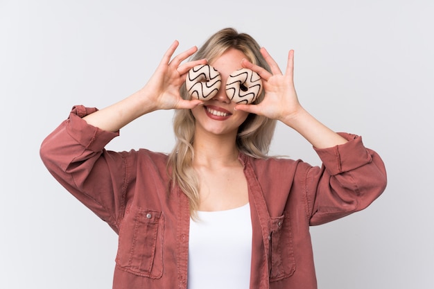 Young woman eating donuts over isolated wall