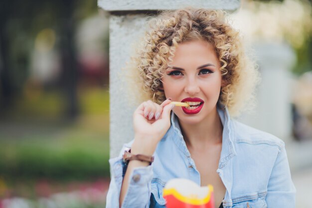 Giovane donna che mangia patatine fritte cibo di strada