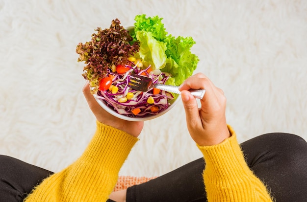 Young woman eating fresh salad meal vegetarian spinach in a bowl