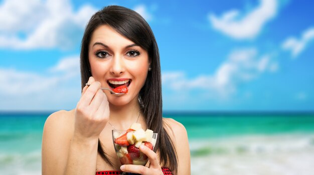 Young woman eating a fruit cocktail outdoor