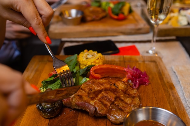 Young woman eating grilled steak in restaurant