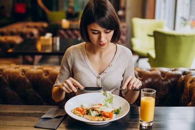 Giovane donna che mangia una sana colazione con succo in un caffè