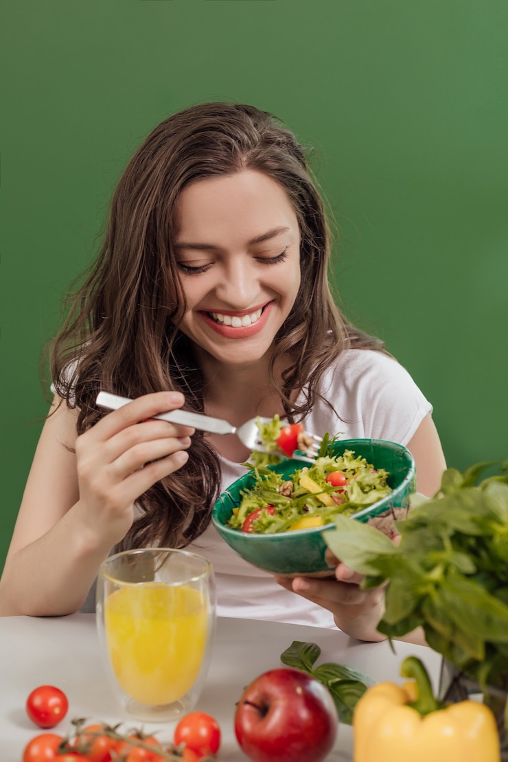 Photo young woman eating healthy food at green background