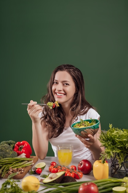 Young woman eating healthy food at green background