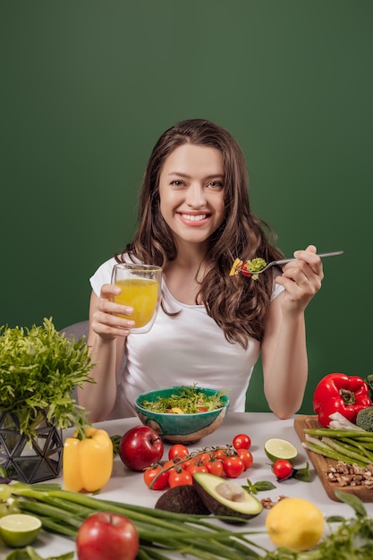 Young woman eating healthy food at green background