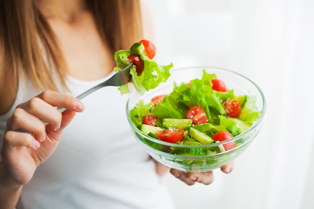 Young woman eating healthy salad after workout