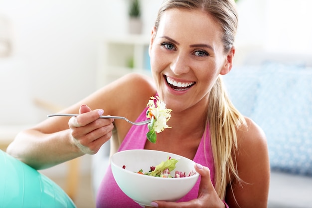 Foto giovane donna che mangia insalata sana dopo l'allenamento