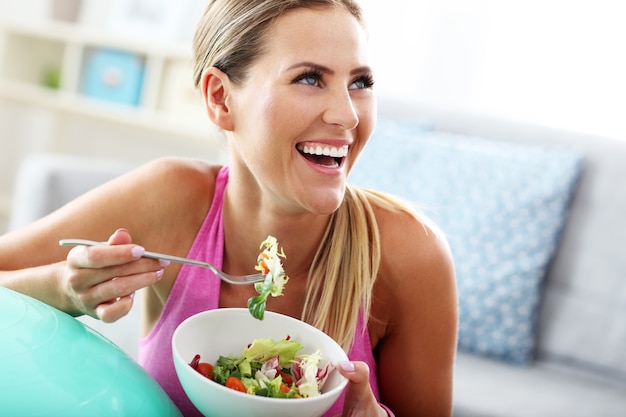 Foto giovane donna che mangia insalata sana dopo l'allenamento