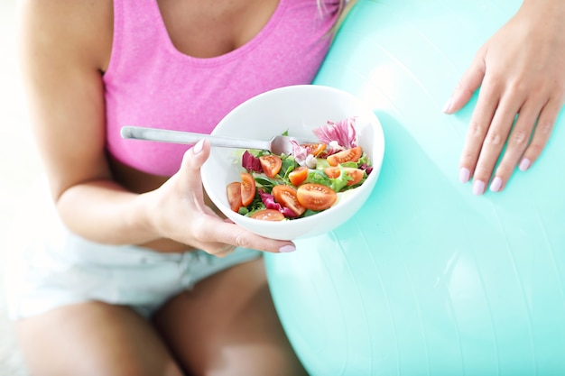 Young woman eating healthy salad after workout