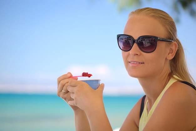 Young woman eating ice-cream on the beach