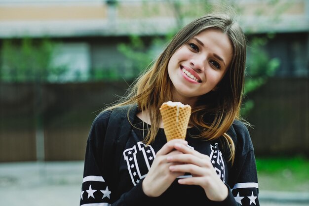 Young woman eating icecream sunny day outdoors near big house